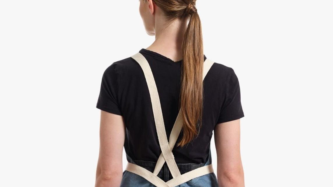 Person wearing a blue apron over a black shirt on a white background